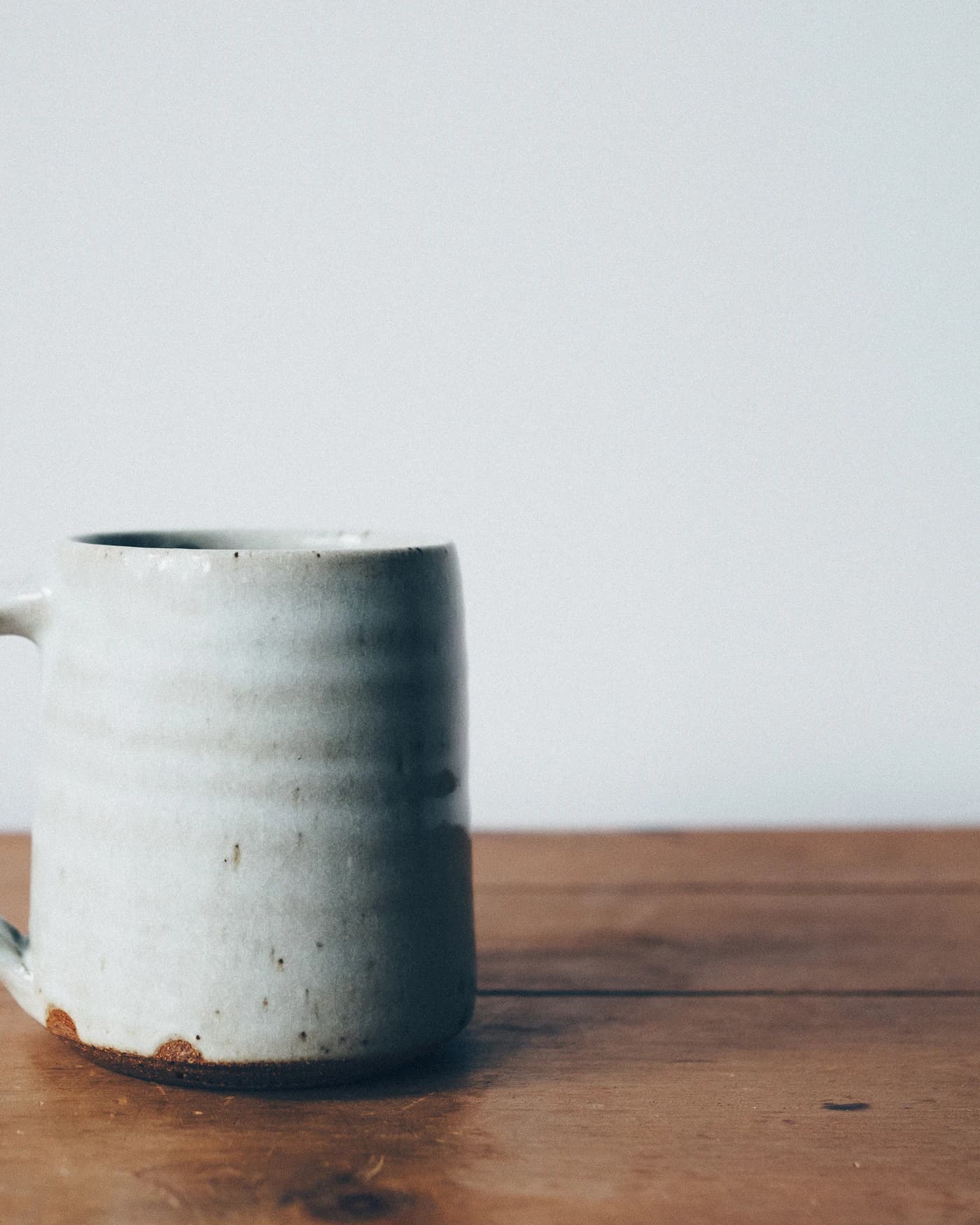 Caneca de cerâmica artesanal sobre mesa de madeira