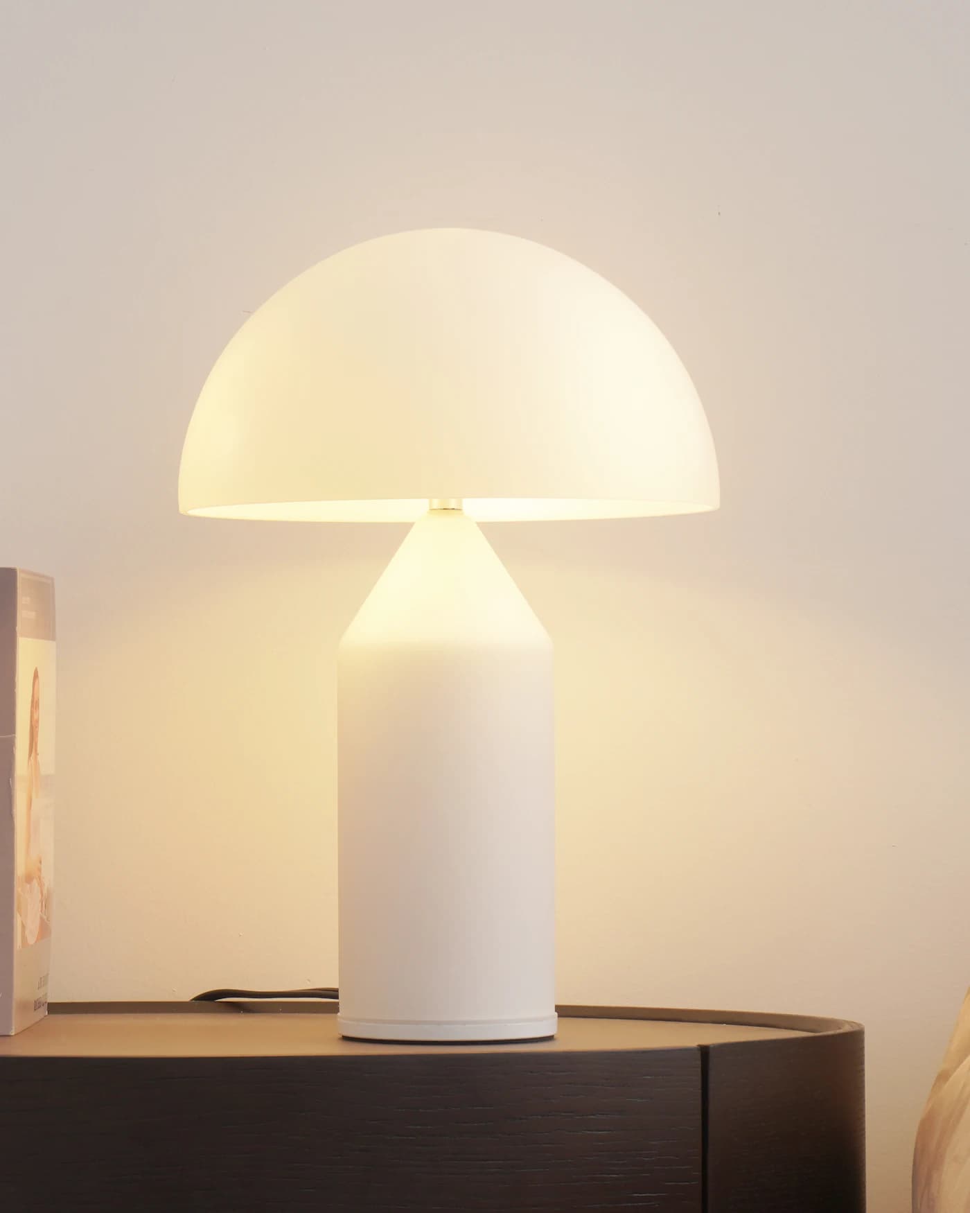 Luminária de mesa acesa ao lado de vaso e livros